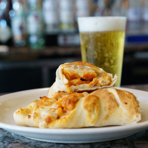 Buffalo Chicken Roll with glass of beer placed behind it.
